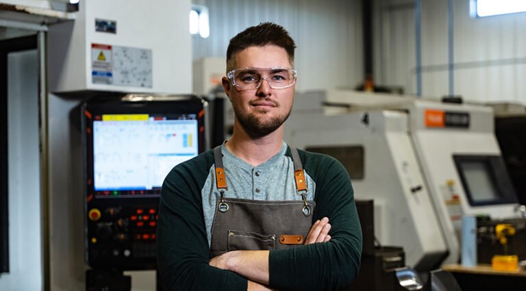 A man wears safety glasses and a protective apron.