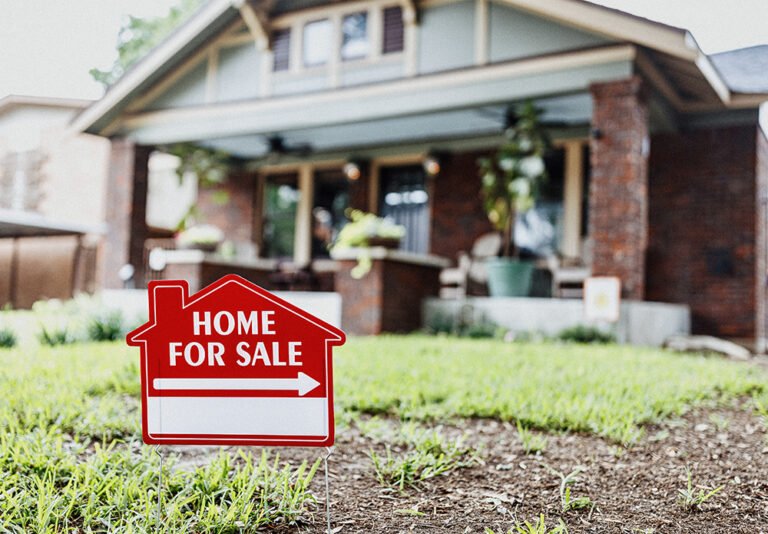 A home for sale sign in front of a house with a porch.
