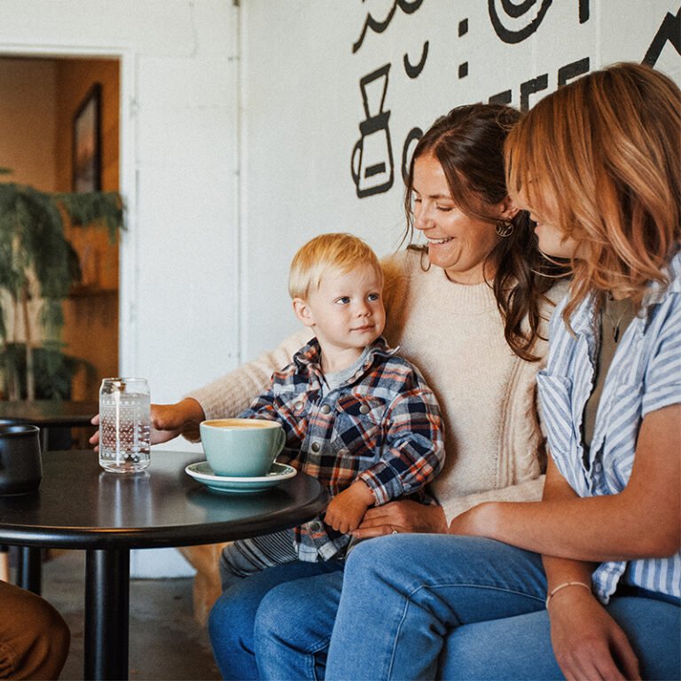 Two women and a small boy sit at a table in a coffee shop.