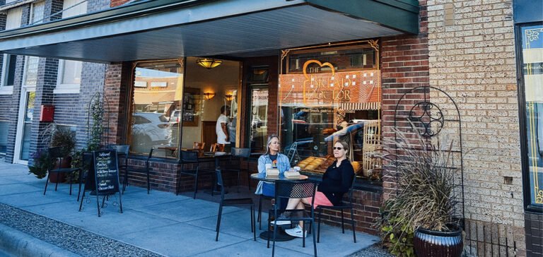 Two women sit at an outdoor table.